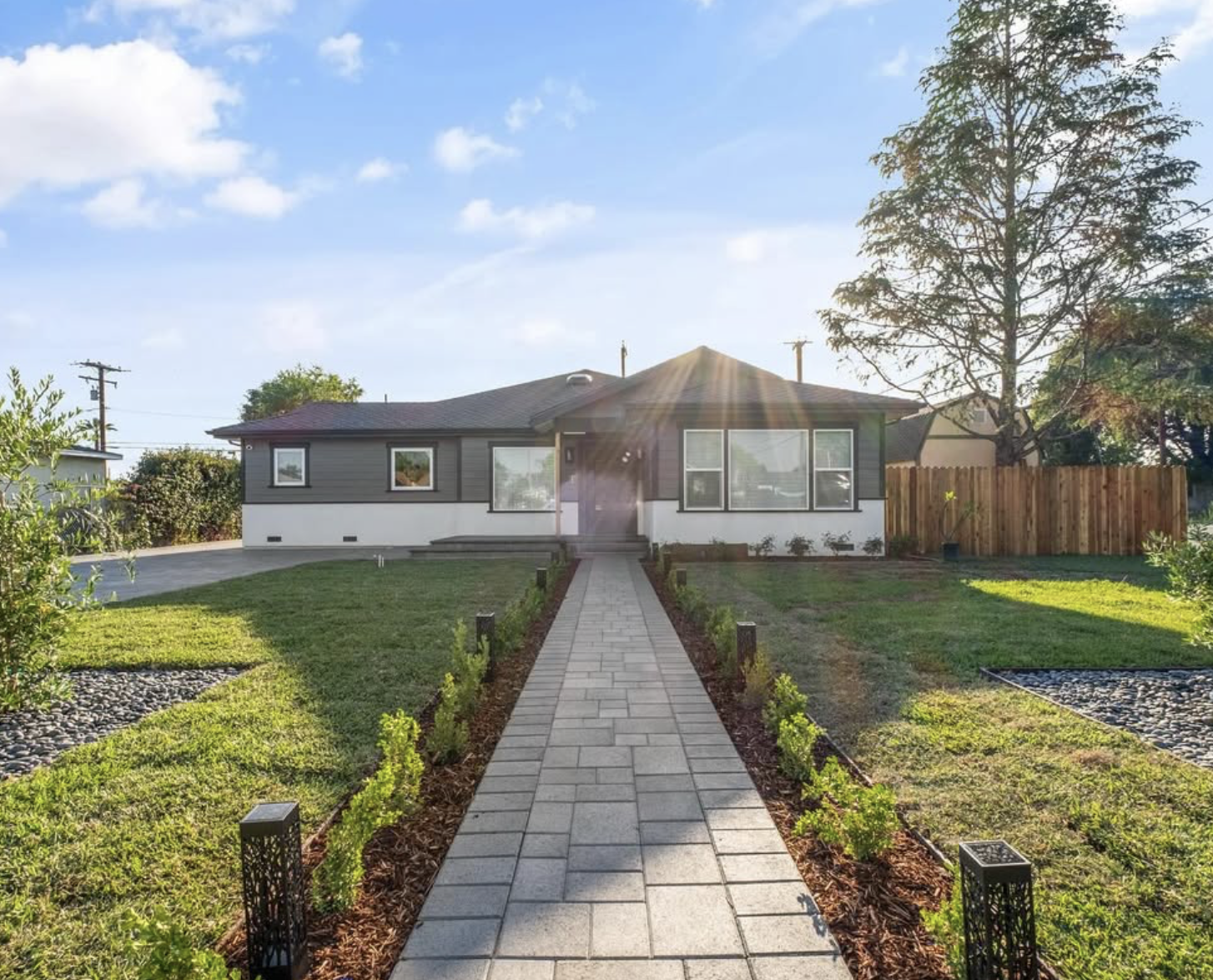 Completed front yard project by D&M Landscaping featuring a custom paver walkway, fresh sod, planting beds, and new wood fence